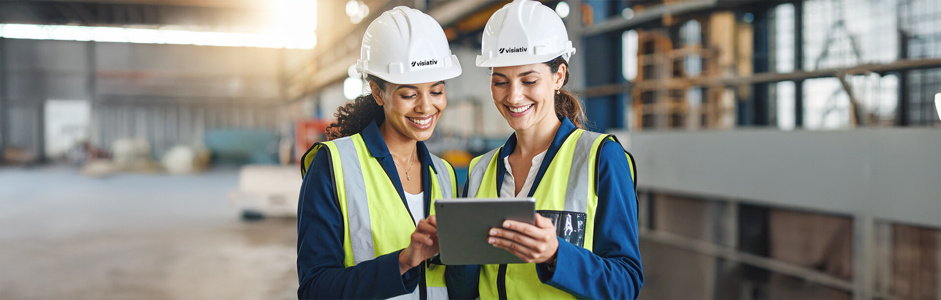 Two female engineers working on a tablet in protective clothing