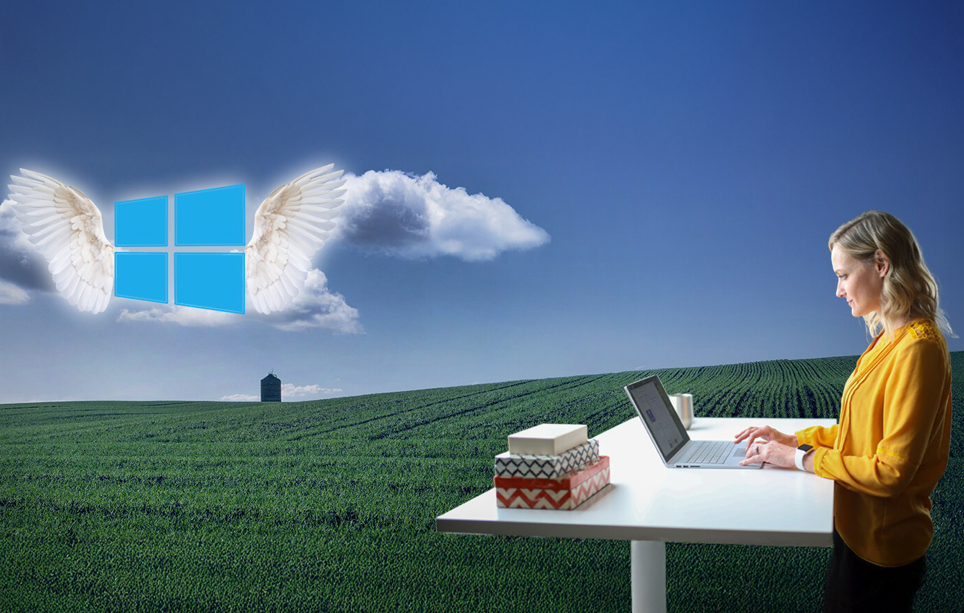 An image of Windows 10 with angel wings in the sky and a person on a laptop in the foreground.