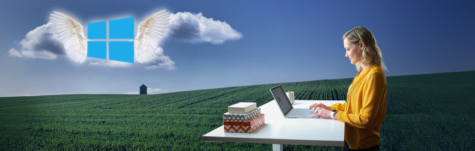 An image of Windows 10 with angel wings in the sky and a person on a laptop in the foreground.