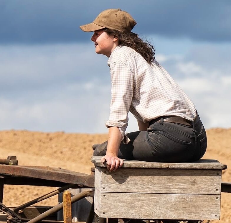 A photo of the Founder of Gradely Engineering, Lilly Day, sitting on an old piece of machinery